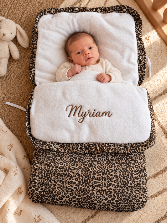 Nid d'ange Léopard avec bébé installé, prénom brodé sur le rabat en polaire blanche