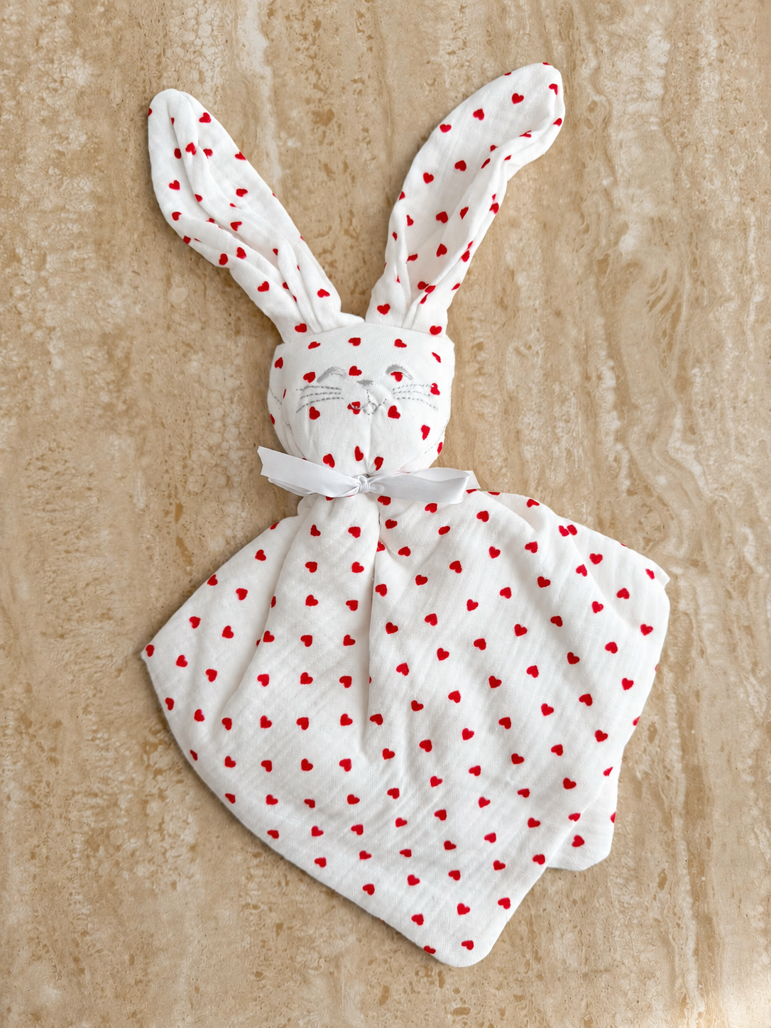 Doudou lapin Petit Cœur en gaze de coton à petits cœurs rouges, posé à plat