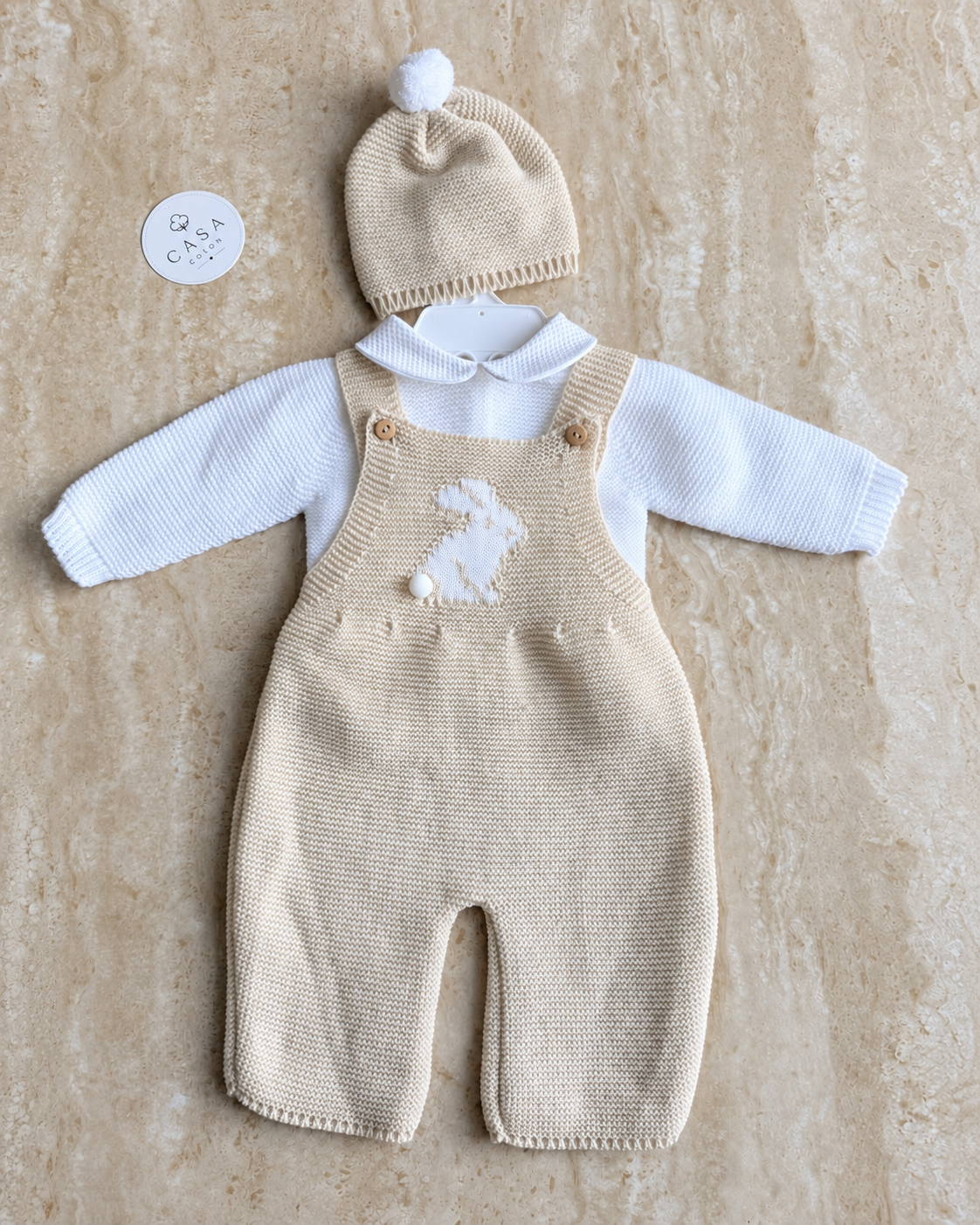 Ensemble bébé Sacha en maille beige : salopette, brassière et bonnet présentés à plat