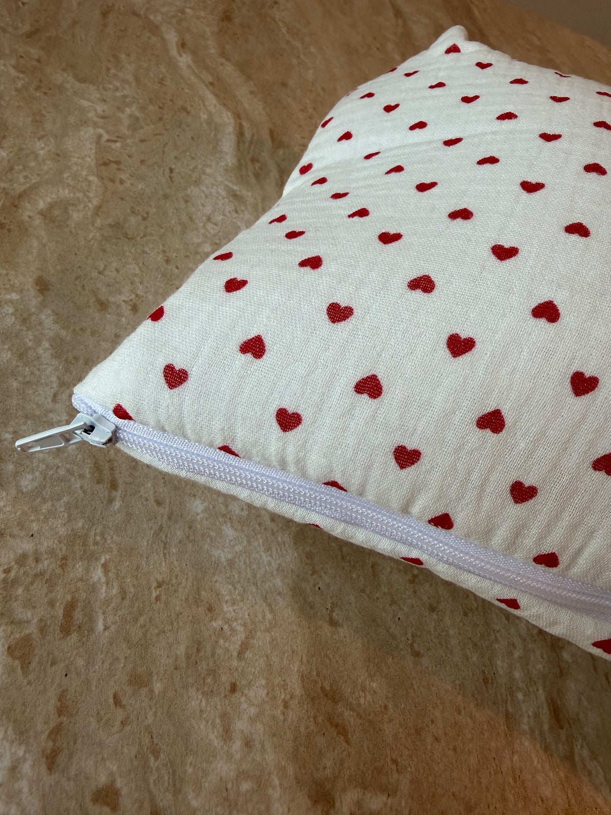Gros plan sur le motif à petits cœurs rouges et la fermeture éclair de la trousse de toilette Petit Cœur