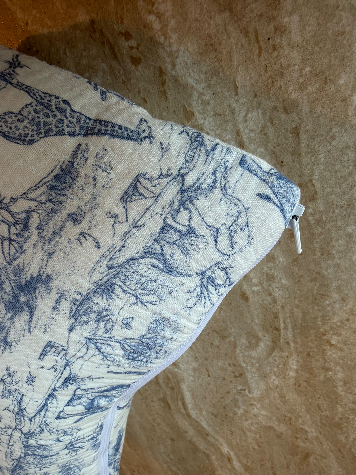 Gros plan sur le motif en toile de Jouy bleue et la fermeture éclair de la trousse de toilette Safari bleue