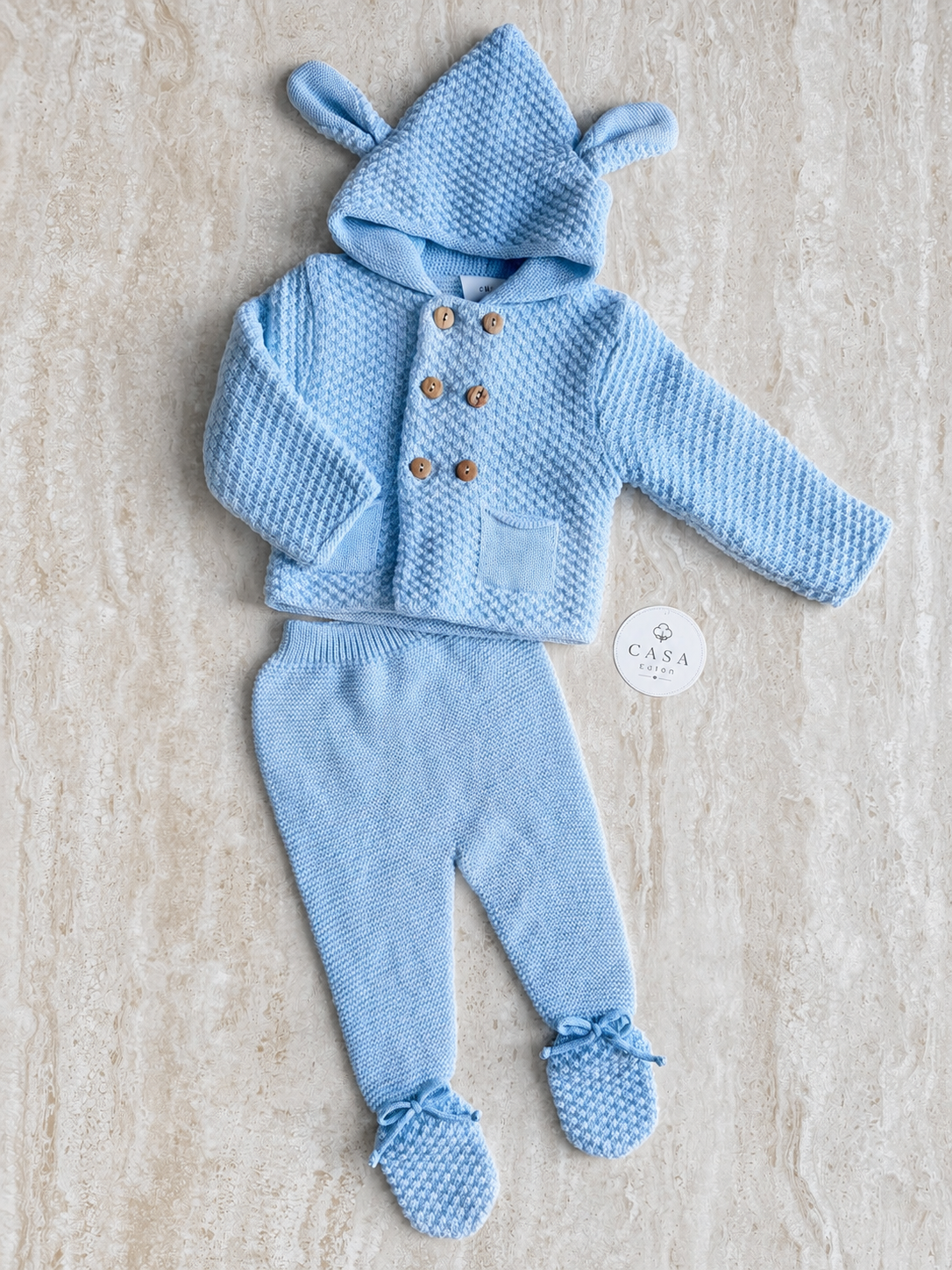 Ensemble bébé Noé en maille bleu ciel, veste croisée à capuche et pantalon présentés à plat