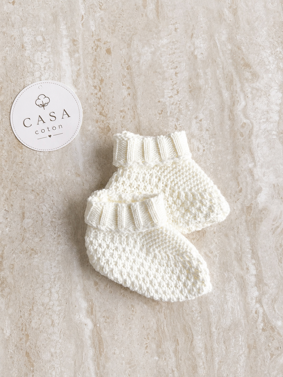 Chaussons bébé Noa en maille blanche, présentés à plat