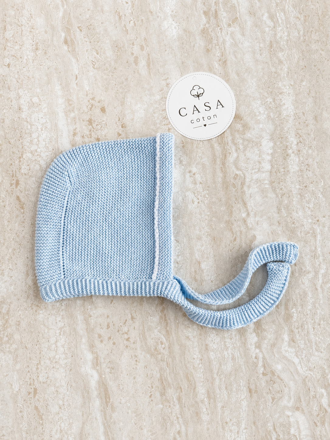Bonnet bébé Gabriel en maille bleu ciel façon béguin noué sous le menton