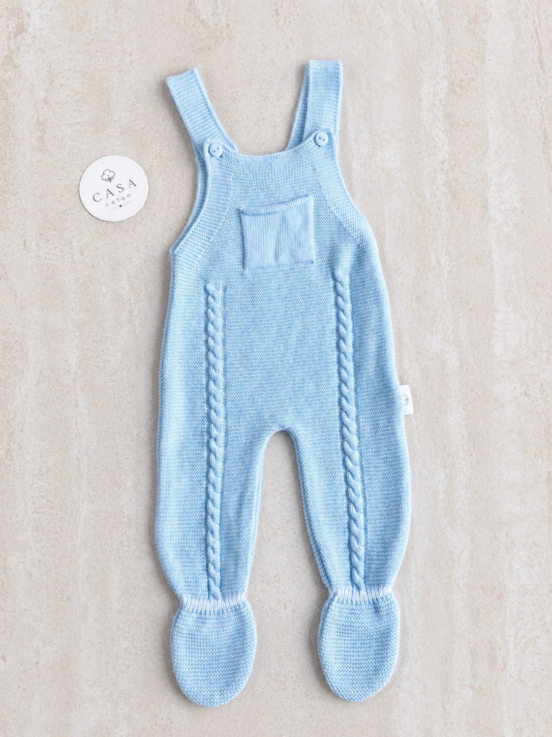 Salopette bébé Gabriel en maille bleu ciel, présentée à plat