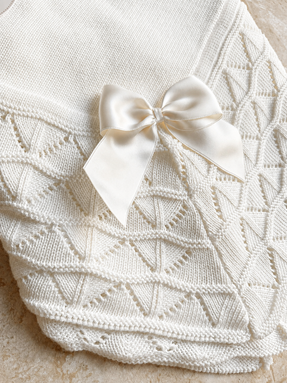 Détail du point ajouré et du nœud satin de la couverture bébé Luna blanche