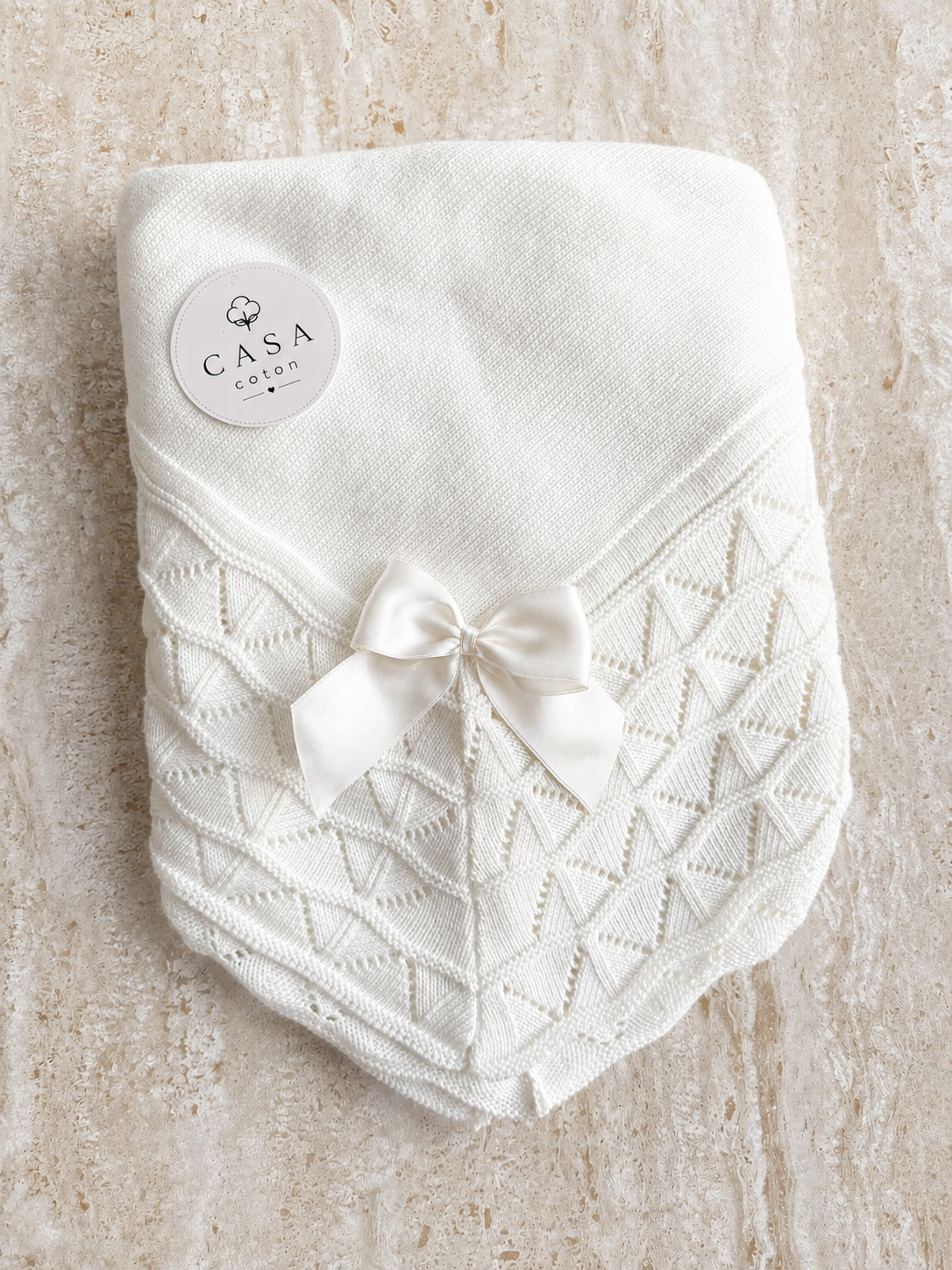 Grande couverture bébé Luna en maille blanche, pliée avec son nœud