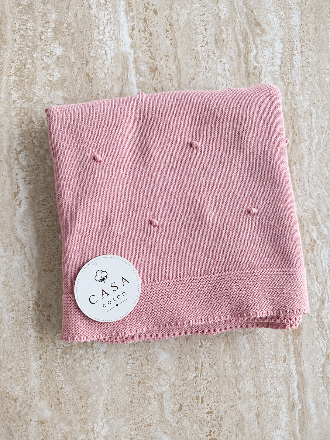 Grande couverture bébé Léo en maille popcorn rose, pliée