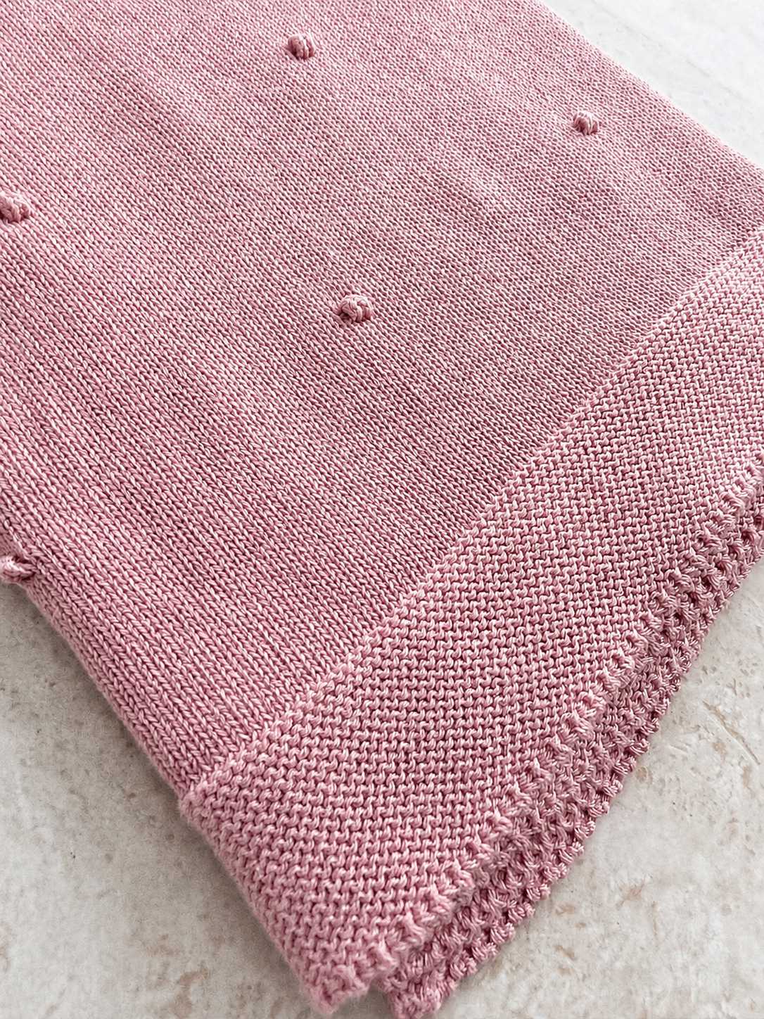 Détail de la maille popcorn texturée de la couverture bébé Léo rose