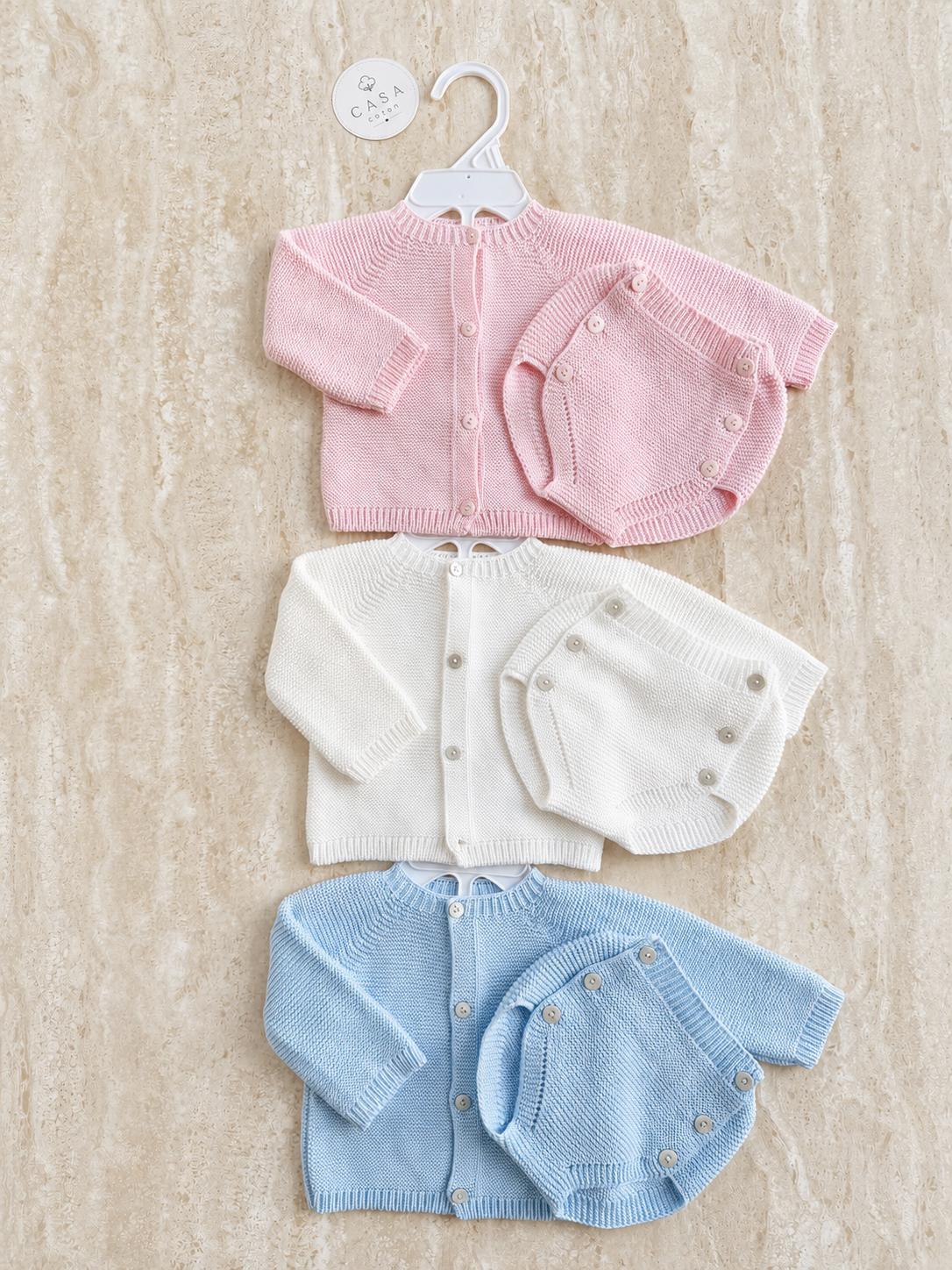 Ensemble bébé Léna en maille, hauts et pantalons rose, blanc et bleu présentés à plat