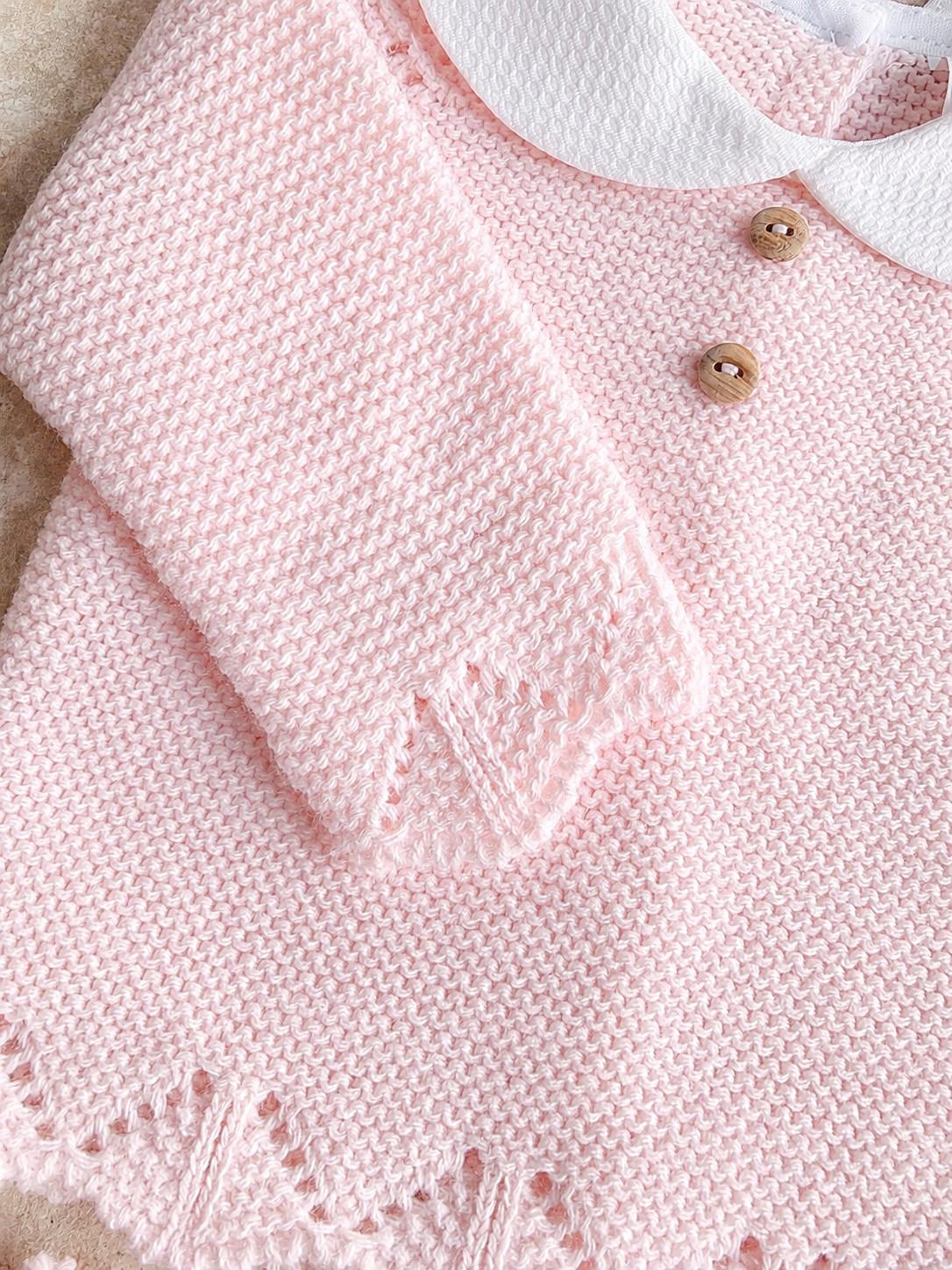 Détail de la maille et des boutons bois de l’ensemble bébé Gabriela rose