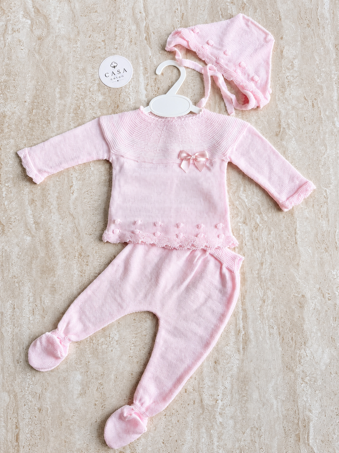 Ensemble bébé Elena en maille rose, brassière, pantalon et bonnet présentés à plat