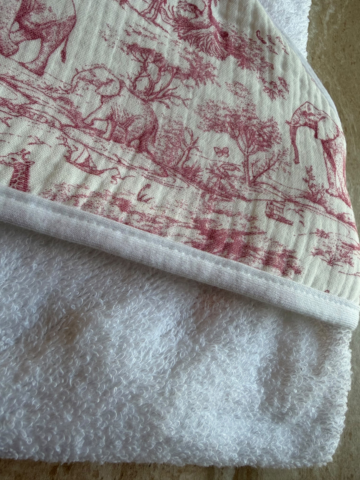 Gros plan sur la capuche en toile de Jouy rose et l'éponge blanche de la cape de bain Safari